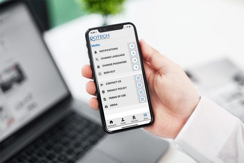 Rotech App displayed on phone held by man's hand in office environment