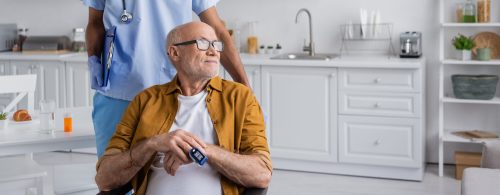 Elderly man wearing a pulse oximeter at home with a nurse