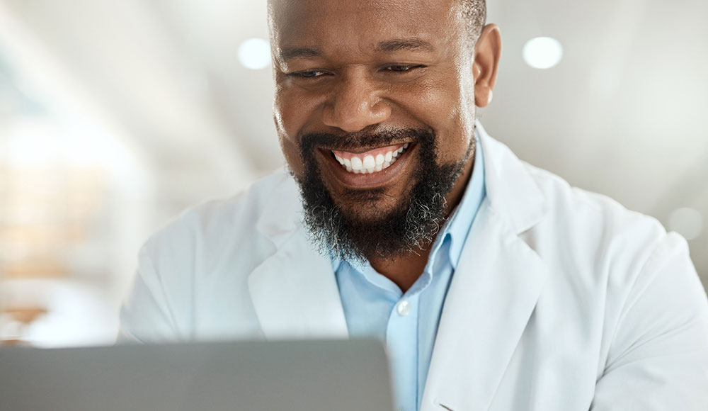 Male doctor smiling at a computer