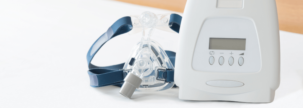 CPAP machine with mask sitting on bed