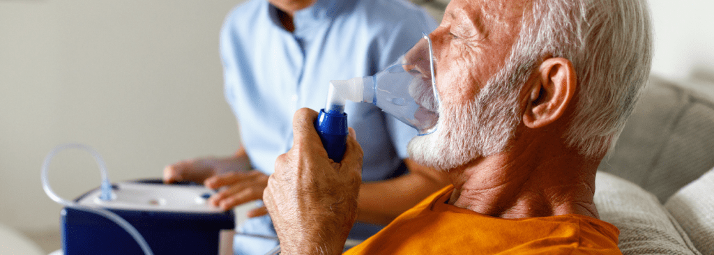 Man holding oxygen mask to his face with healthcare professional in the background