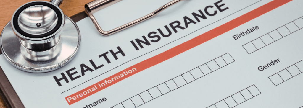 Close up of clipboard with document on it that says Health Insurance at the top and a stethoscope resting upon it