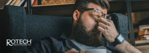 Man rubbing his eyes behind his glasses from tiredness