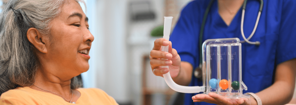 Physical therapist assisting mature woman with using a spirometer to improve the functioning of lungs.