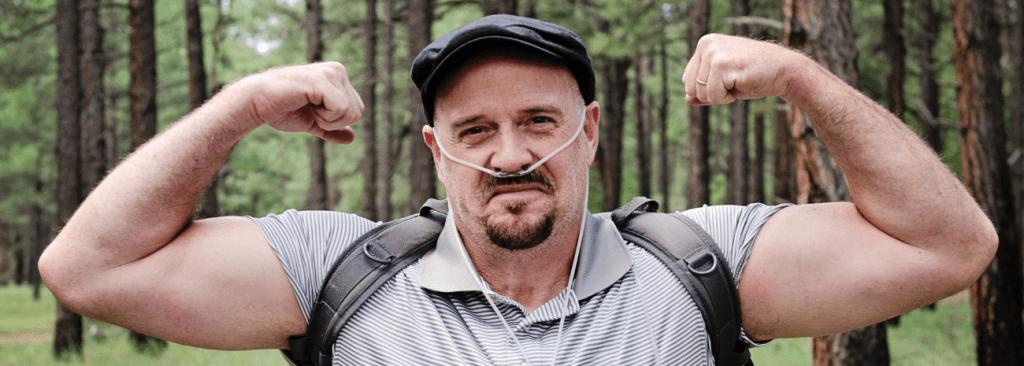 Man with supplemental oxygen on flexing outdoors in the woods