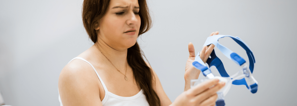 Woman holding up CPAP mask with confused look on her face