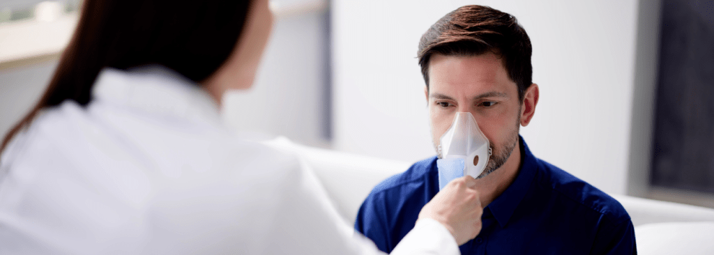 Man with oxygen mask being put on face by doctor