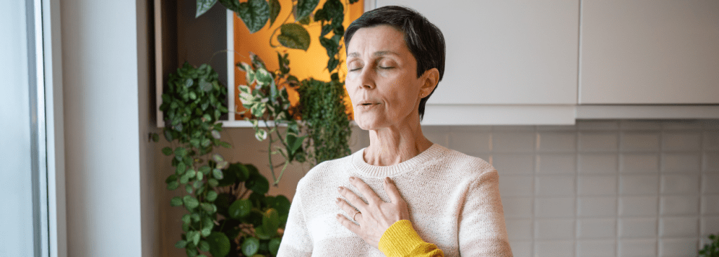 Woman practicing pursed lip breathing while standing in her kitchen
