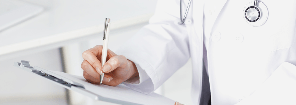 Healthcare professional writing on clipboard with pen