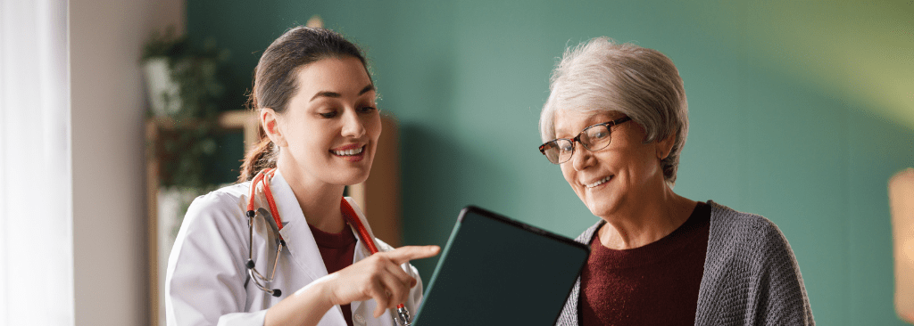Female doctor speaking to senior woman while looking at tablet together