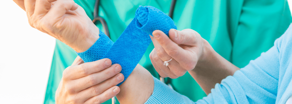 Healthcare professional wrapping blue gauze around a woman's forearm