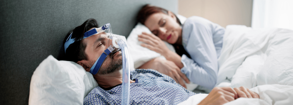 Man sleeping with CPAP mask on with wife next to him