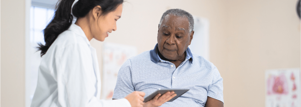 Older male patient speaking with female healthcare professional at doctor's office