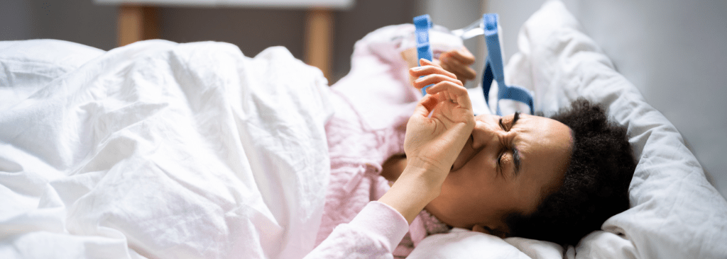 Man removing CPAP mask while lying in bed