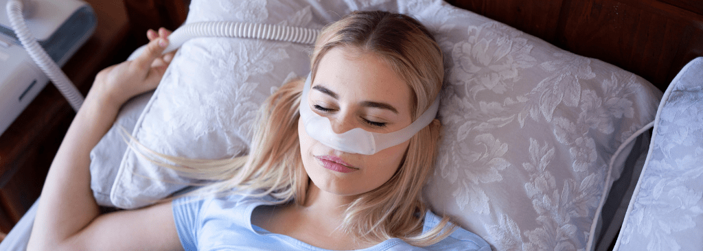 Woman sleeping in bed with nasal CPAP mask on her face