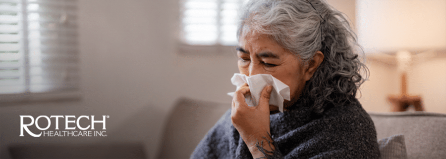 Senior woman on couch blowing her nose with tissue