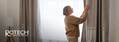 Senior woman opening curtains at her home
