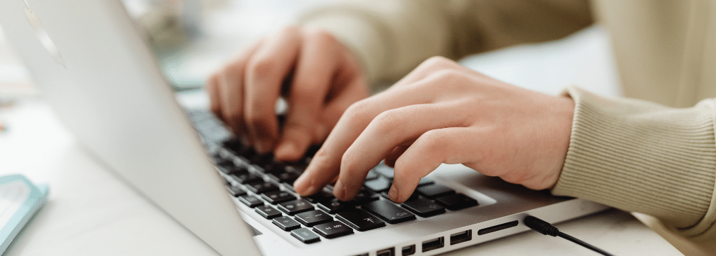 Person's hands typing on a laptop on a desk