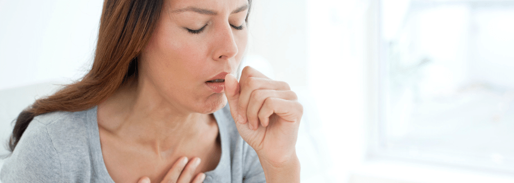 Woman with hand on chest while coughing