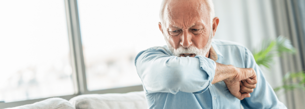 Senior man coughing into his elbow