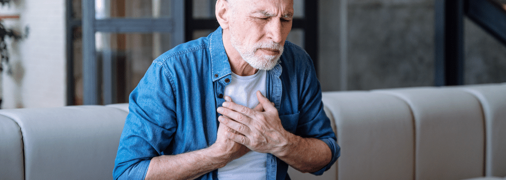 Senior man with hands to his chest to indicate difficulty